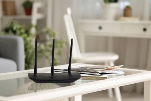 Modern wi-fi router and magazines on table in living room, closeup