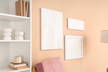 Oturma odasındaki bej duvarda asılı şık resimler.