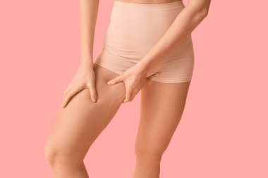 Pembe arka planda selülit sorunu olan güzel bir genç kadın.