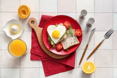 Lezzetli kızarmış yumurta, tost, domates, roka ve açık fayanslı bir bardak meyve suyu.