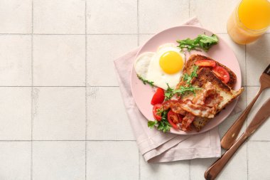 Lezzetli sahanda yumurta, tost, pastırma, domates ve arka planda bir bardak meyve suyu.