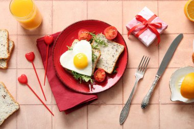 Tabakta leziz sahanda yumurta, bir bardak meyve suyu ve bej fayanslı hediye kutusu.