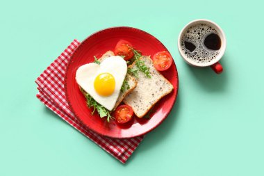 Lezzetli kızarmış yumurta, tost, domates, roka ve turkuaz arka planda bir fincan kahve.