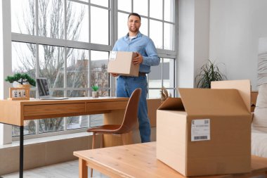 Evde paketle gülümseyen genç adam.