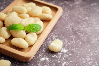 Lezzetli gnocchi ve fesleğenli ahşap tahta, yakın plan.