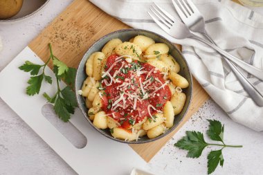 Beyaz arka planda domates soslu ve peynirli bir kase lezzetli gnocchi.