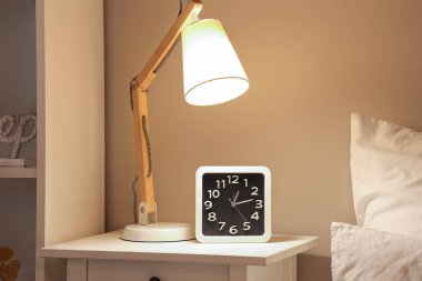 Parlayan lamba ve saat gece başucunda, yakın plan.