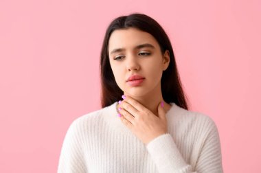 Pembe arka planda tiroit bezi sorunu olan genç bir kadın.