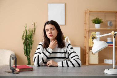 Tiroid bezi sorunu olan genç bir kadın oturma odasında oturuyor.