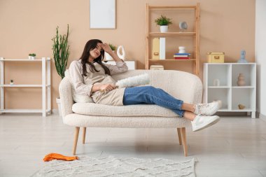 Oturma odasındaki kanepede uzanan tozlu, yorgun genç bir kadın.