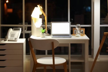 Ofisteki masasında parlak lamba olan boş bir laptop.