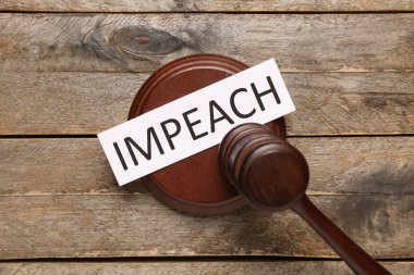 Judge gavel with word IMPEACH on wooden background