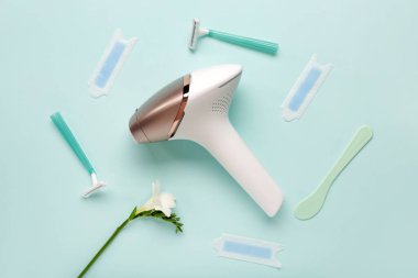 Mavi arka planda ustura, balmumu şeritli ve çiçekli modern fotoepilatör.