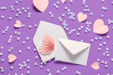 Zarflı kompozisyon, kağıt kalpler ve mor arka planda cam taşlar. Sevgililer Günü kutlaması