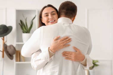 Evinde kocasına sarılan mutlu genç bir kadın.