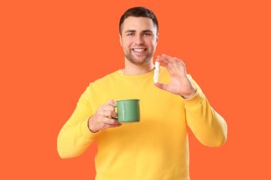 Turuncu arka planda çay ve şeker küpleri olan genç bir adam.