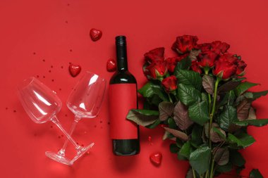 Kırmızı arka planda bir şişe şarap, güller ve dekor. Sevgililer Günü kutlaması