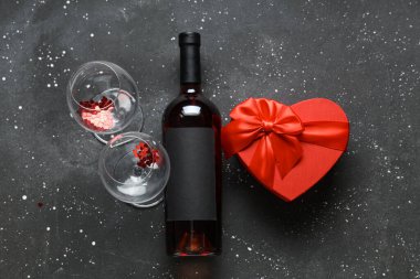 Siyah arka planda bir şişe şarap ve hediye kutusu. Sevgililer Günü kutlaması