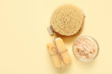 Açık sarı arka planda sabun ve fırçayla fırçala. Vücut masajı konsepti