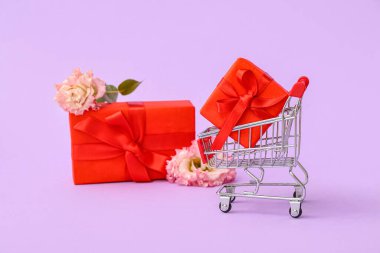 Hediye kutularıyla küçük alışveriş arabası ve leylak arka planında çiçekler. Sevgililer Günü kutlaması