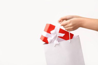 Kağıt alışveriş torbası ve beyaz arka planda hediye kutusu olan kadın elleri. Sevgililer Günü kutlaması