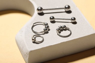 Bej arka planda piercing için halkalar ve halkalarla sıva podyum