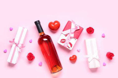 Pembe arka planda hediyeler ve dekor olan bir şişe şarap. Sevgililer Günü kutlaması