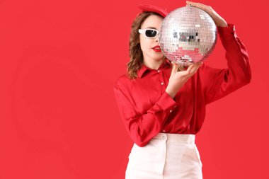 Kırmızı arka planda disko topu olan şık güneş gözlüklü güzel bir kadın.