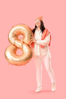 Güzel, mutlu, olgun bir kadın. Pembe arka planda 8 şeklinde büyük bir balonu var. Uluslararası Kadınlar Günü