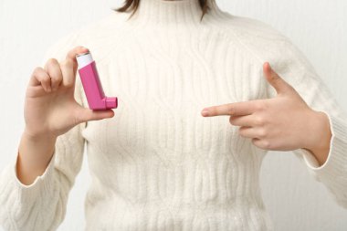 Beyaz arka planda astım spreyi olan çocuk, yakın plan