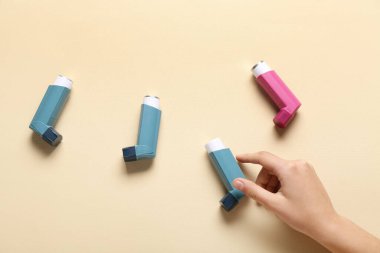 Bej arka planda astım spreyleri olan bir çocuk eli.