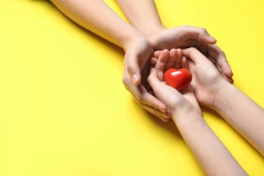 Sarı arka planda kırmızı kalpli kadın ve çocuğun elleri