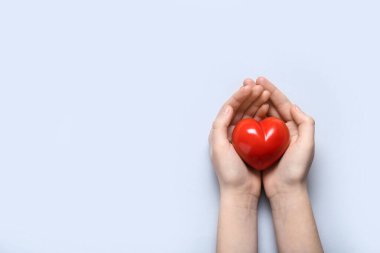 Gri arka planda kırmızı kalpli kadın elleri