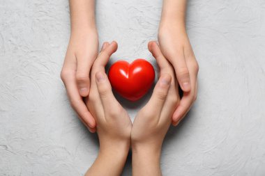 Beyaz arka planda kırmızı kalpli kadın ve çocuğun elleri