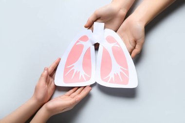 Gri arka planda kağıt ciğerli kadın ve çocuğun elleri