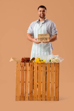 Bej arka planda çiçek satan genç adam.