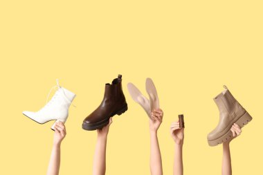 Çizmeleri, tabanları ve sarı arka planda dikiş ipliği olan kadın elleri. Ayakkabı tamiri kavramı