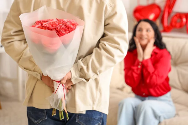 Mature man with bouquet of roses for his beloved wife at home. Valentine\'s Day celebration