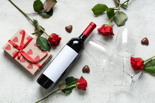 Bottle of wine with glasses, gift box, chocolate candies and red roses on white background. Valentine\'s Day celebration