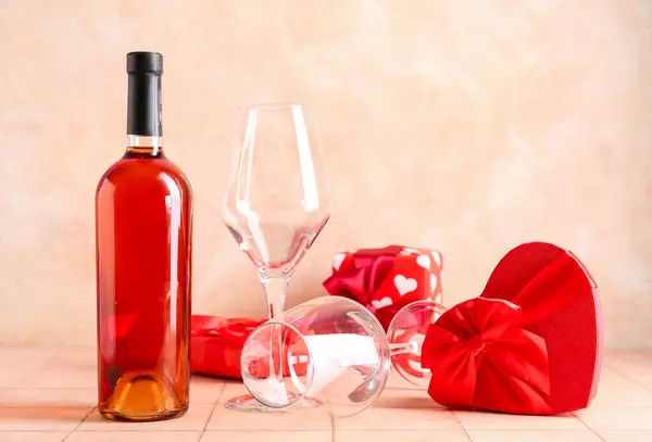 グラウンジの背景に対するベージュタイルテーブルのグラスとギフトでワインのボトル バレンタインデーのお祝い — ストック写真