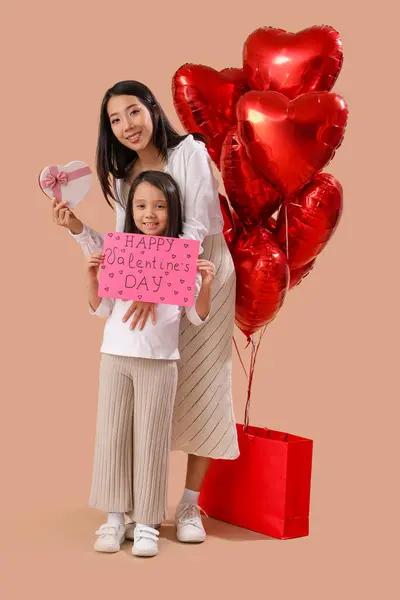 快乐的亚洲女人 带着她的小女儿带着礼品卡 购物袋和棕色背景的心形气球 情人节庆祝活动 — 图库照片