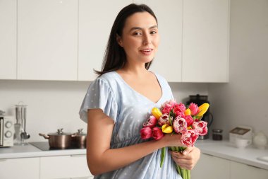 Mutfakta bir buket güzel lalesi olan genç bir kadın. Uluslararası Kadınlar Günü
