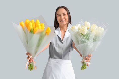 Hafif arka planda lale buketleri olan genç oda hizmetçisi. Uluslararası Kadınlar Günü
