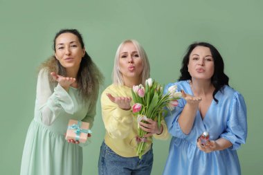 Bir buket güzel lalesi, parfümü ve yeşil arka planda öpüşen hediye kutusu olan olgun kadınlar. Uluslararası Kadınlar Günü