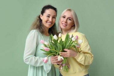 Yeşil arka planda bir buket güzel lalesi olan olgun kadınlar. Uluslararası Kadınlar Günü