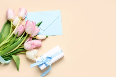 Sarı arka planda hediye kutusu ve zarfı olan bir buket güzel lale. Uluslararası Kadınlar Günü