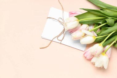 Bir buket güzel lale ve pembe arka planda bir zarf. Uluslararası Kadınlar Günü