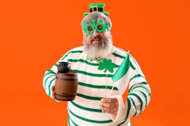 Fıçı ve turuncu arka planda İrlanda bayrağı olan olgun bir adam. Aziz Patrick Günü kutlaması