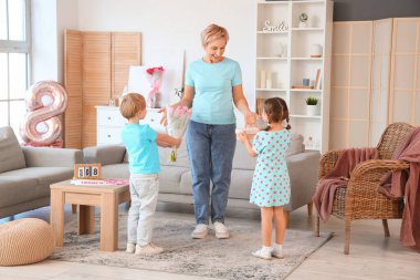 Yetişkin bir kadın, evde torunlarından hediyeler alıyor. Uluslararası Kadınlar Günü