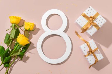 Hediye kutuları ve pembe arka planda güzel sarı gülleri olan sekiz numara. Uluslararası Kadınlar Günü